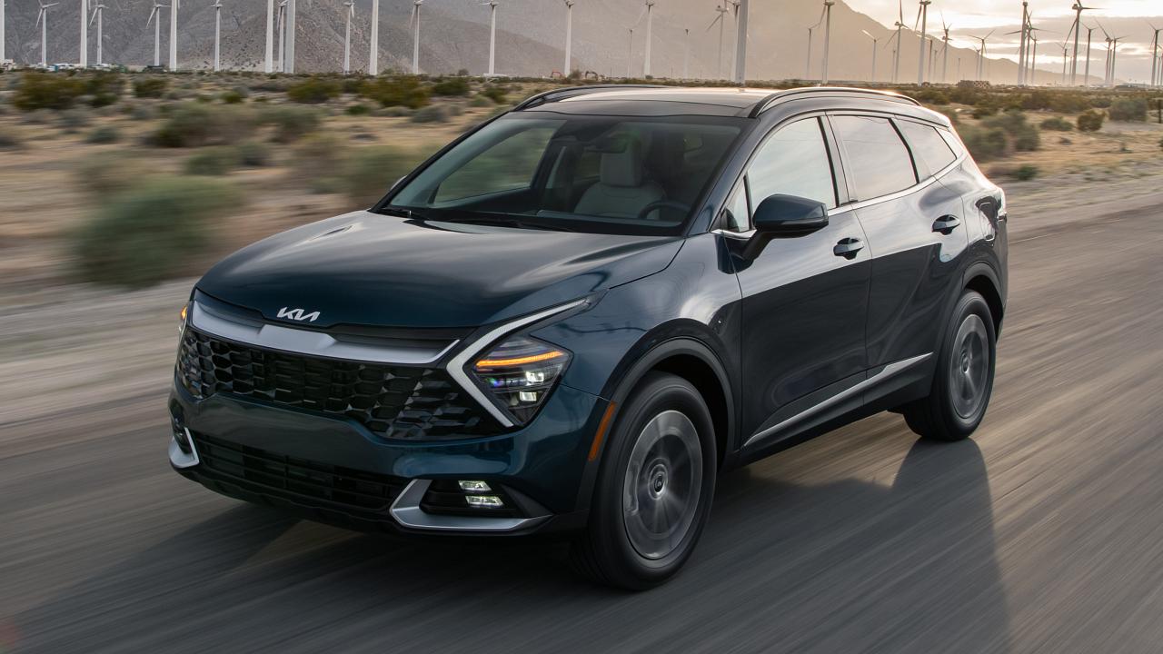 2024 Kia Sportage Hybrid driving past a wind farm